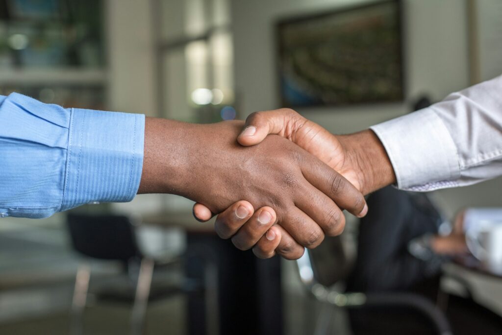 A handshake between two individuals in an office, representing a warm agreement and trust.